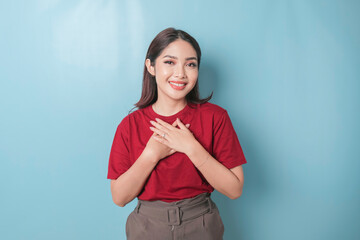 Happy mindful thankful young woman holding hands on chest smiling isolated on blue background...