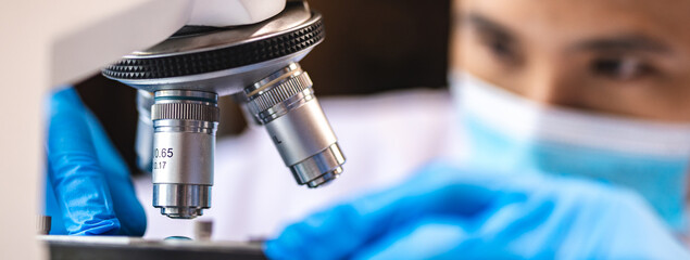 Scientist analyzing microscope slide at laboratory. Young woman technician is examining a...