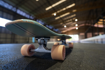 closeup pink skate wheel on back tail skateboard or surfskate to street skate on indoor pump track in school skatepark and nobody for extreme sports and fun exercise on summer by warm and cool light