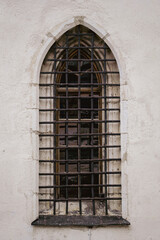 Old white stone wall with one arched grating window on the street, Austria