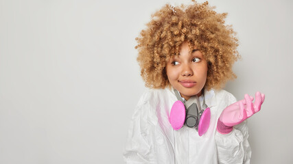 Hesitant woman shrugs shoulders wears chemical suit and respirator works at plant doesnt know how...