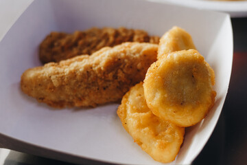 Close up of chicken nuggets in basket with parchment paper and chili tomato sauce on wooden background.