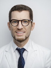 Portrait of happy young bearded male doctor smiling with eyeglasses isolated on white background