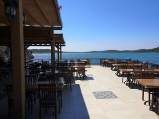 Terrasse eines Restaurant mit Panoramablick im Sommer vor blauem Himmel im Sonnenschein am Strand...