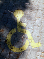 Parkplatz für Rollstuhlfahrer gelb markiert auf grauem Verbundpflaster im Sonnenschein am Strand...