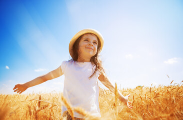 Happy girl walking enjoying the life in the golden field. Nature beauty, sunny blue sky and yelow field of wheat. Family outdoor lifestyle. Freedom concept. Cute little girl in summer field - 521803033