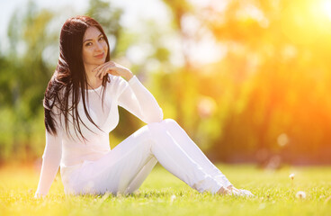 Young woman relax in the early autumn park on green grass. Beauty nature scene with colorful background, trees at fall season. Outdoor lifestyle. Happy smiling woman sitting on green grass - 521803042