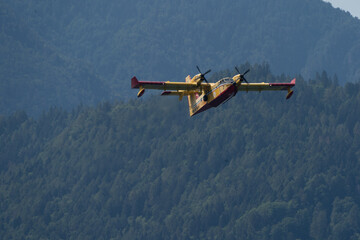 Fototapeta na wymiar flying seaplane taking up water in Caldonazzo lake during a fire