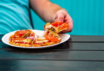 man Hand takes a slice of meat pita Pizza with Mozzarella cheese, ham, bacon, tomato, Spices in...