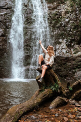 Naklejka na ściany i meble Travel. Girl travels through the mountains and waterfalls of wild nature. Unity, mental health, eco travel. Hiking in the mountains, van life vibes, travelling,good moments, digital detox
