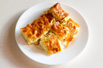 Turkish style meat stuffed filo dough borek served kol boregi. Cheese and minced pie are sliced on a marble background. Turkish name: Kol Boregi, kiymali, peynirli su boregi.