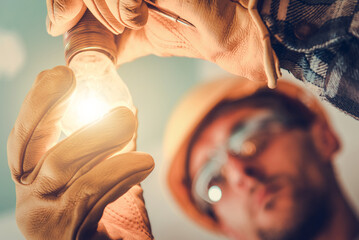 Glowing Light Bulb in the Hands of an Electrician