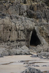 A photograph of an eerie cave entrance on a beach
