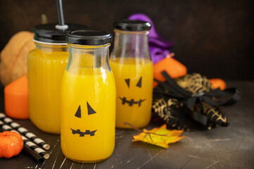 Pumpkin drink on a festive halloween table and Halloween pumpkins, lantern and decoration on dark stone background. Copy space.
