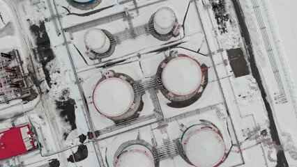 Drone flies over snow-covered oil tanks. Oil storage tanks for the winter period. A strategic oil...