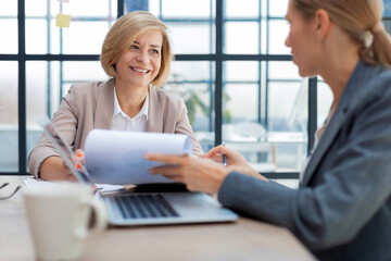 Image of two business women working in the office with documents.