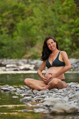 Relaxed pregnant woman in the nature, enjoying a beautiful spot on a river shore.
