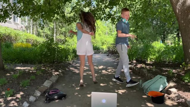 a boy and a girl are dancing on the street, looking into a laptop, a dance master class, a boy and a girl are running their dance blog, showing dance moves to their subscribers.