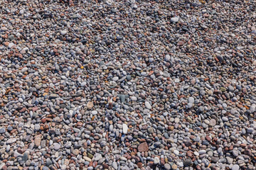 Beautiful view of texture on pebble beach from small multi-colored stones. Greece.