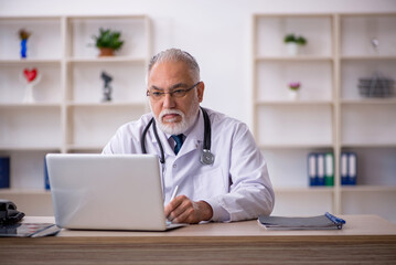 Old male doctor in telemedicine concept