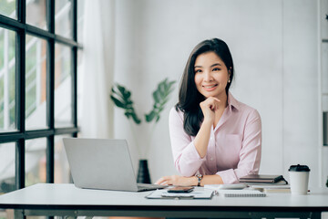 Asian businesswomn sitting working at the office. Looking at camera