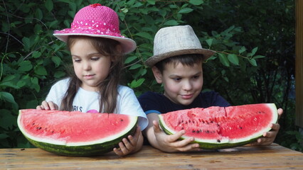 Cute baby girl 3-4 year old and boy eating tasty watermelon over green nature background close up. Healthy lifestyle. Childhood. Summer time. happy satisfied children smiling