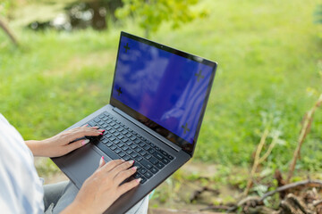Closeup image of a woman working and typing on laptop computer keyboard in the garden
