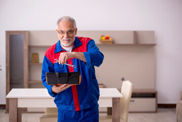 Old male carpenter working indoors