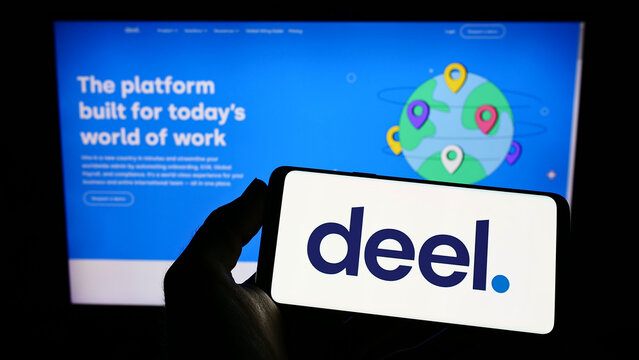 Stuttgart, Germany - 07-30-2022: Person holding smartphone with logo of US payroll solution company Deel Inc. on screen in front of website. Focus on phone display.