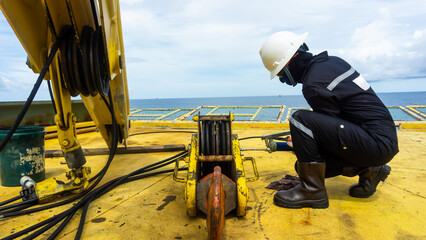 Mechanical engineer inspector is inspecting lifting equipment of pedestal crane on offshore oil and gas wellhead remote platform for yearly preventive maintenance.