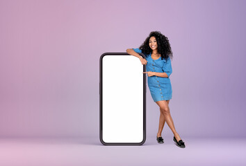 African woman pointing at big phone with empty display, gradient background