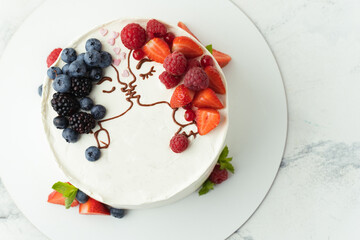 Wedding cake with white cream cheese frosting decorated with blueberries, strawberries and raspberries on top. Silhouette of loving couple kissing. St Valentine's Day cake. Anniversary party cake