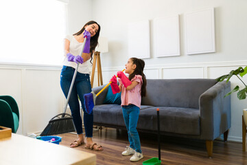 Fun mom and little girl listening to music while doing housework