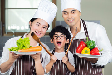 Happy  Asian  family  wearing chef hat.apron  cooking  salad in kitchen at home