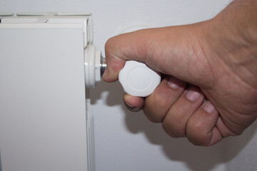 Image of a man's hand turning off a radiator tap due to the excessive price of natural gas. Rising...