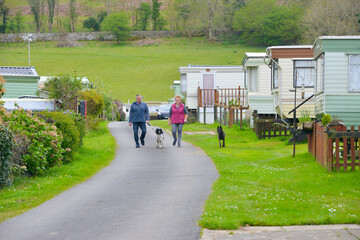 Happy couple and their two dogs enjoy a walk around the caravan site they are staying on in rural...