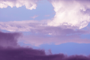 Obraz premium Wild stormy beautiful purple sky with light dark contrasts. Fluffy cumulus clouds in different layers. Surreal abstract bright color background, wind change in cyclone sundown. Horizontal copy space.