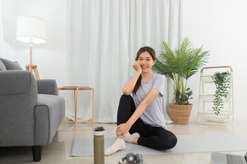 Yoga exercise concept, Young Asian woman sit to relaxing after doing yoga training online at home