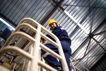 Fototapeta premium Portrait of smiling bearded factory worker in protective work wear looking to the camera over the shoulder.