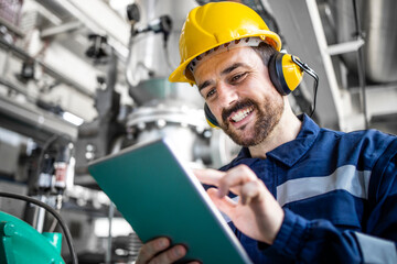 Smiling caucasian worker checking analysis and production on his computer in refinery factory.