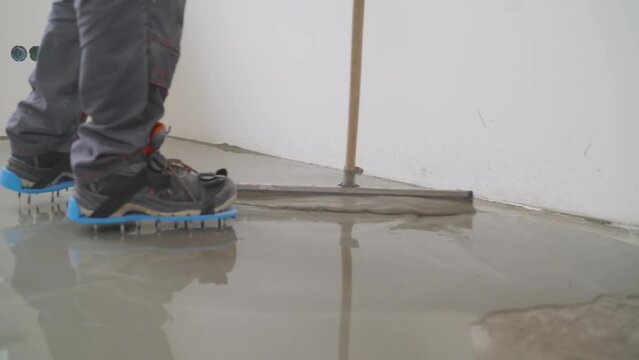 The worker levels the liquid floor. Self leveling epoxy resin. Leveling with a mixture of cement floors. The builder levels the poured concrete floor in a new apartment.