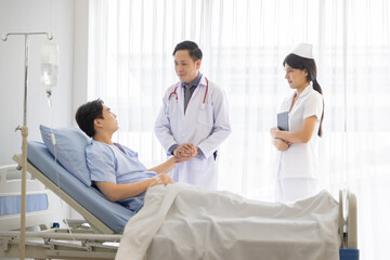 Professional male doctor and nurse caring visiting encourage male patient at hospital