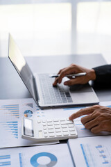 Asian male finance staff is calculating by using a calculator. Investment results to report to his boss at the meeting. On the table in the office, the concept of calculating investment results