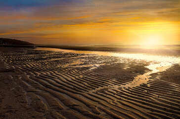 Colorful sunset on the Atlantic coast at low tide in Normandy, France