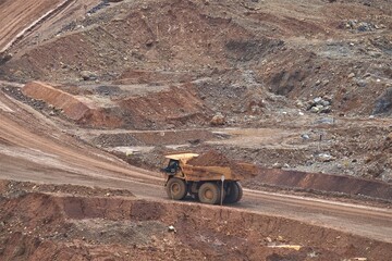 A haul truck is transporting material at a nickel mine site. Rigid dump trucks specifically engineered for use in high-production mining and heavy-duty construction environments.