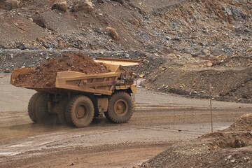 A haul truck is transporting material at a nickel mine site. Rigid dump trucks specifically engineered for use in high-production mining and heavy-duty construction environments.