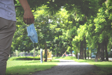 Obraz premium End of coronavirus pandemic. Happy asia guy taking off his protective mask at summer in park. Vintage style