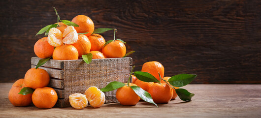 Fresh mandarin oranges fruit or tangerines with leaves in a wooden box