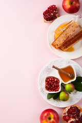 Rosh Hashanah. Honey jar, honeycomb, apple and pomegranate on simple pink background. Jewish New Year holiday greeting card. Rosh Hashanah holiday attributes. Space for text