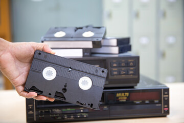 Close-up hand chooses video cassette tape VHS old retro style and press button on video record playback concept of vintage electric and electronic appliances multimedia player device old fashioned.